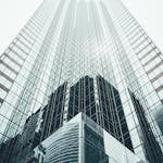 Striking low angle view of a modern skyscraper with reflective glass facade in a cityscape.